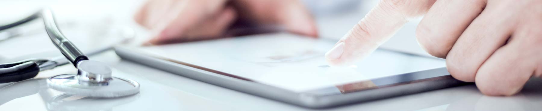 Doctor touching a tablet with stethoscope laying on desk